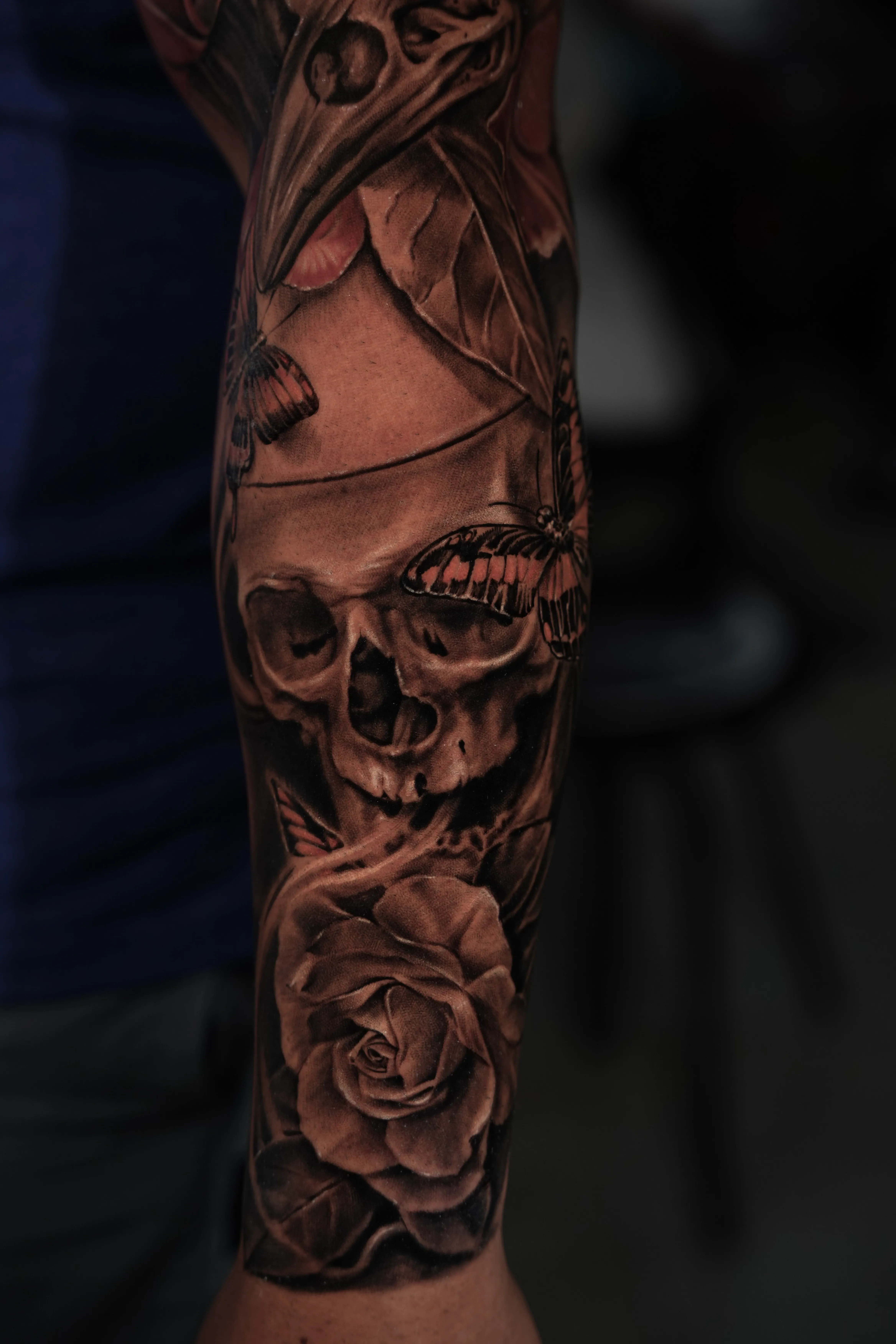 Realism skull with roses and butterflies, subtle color accents — TKOTATTOO Fort Lauderdale