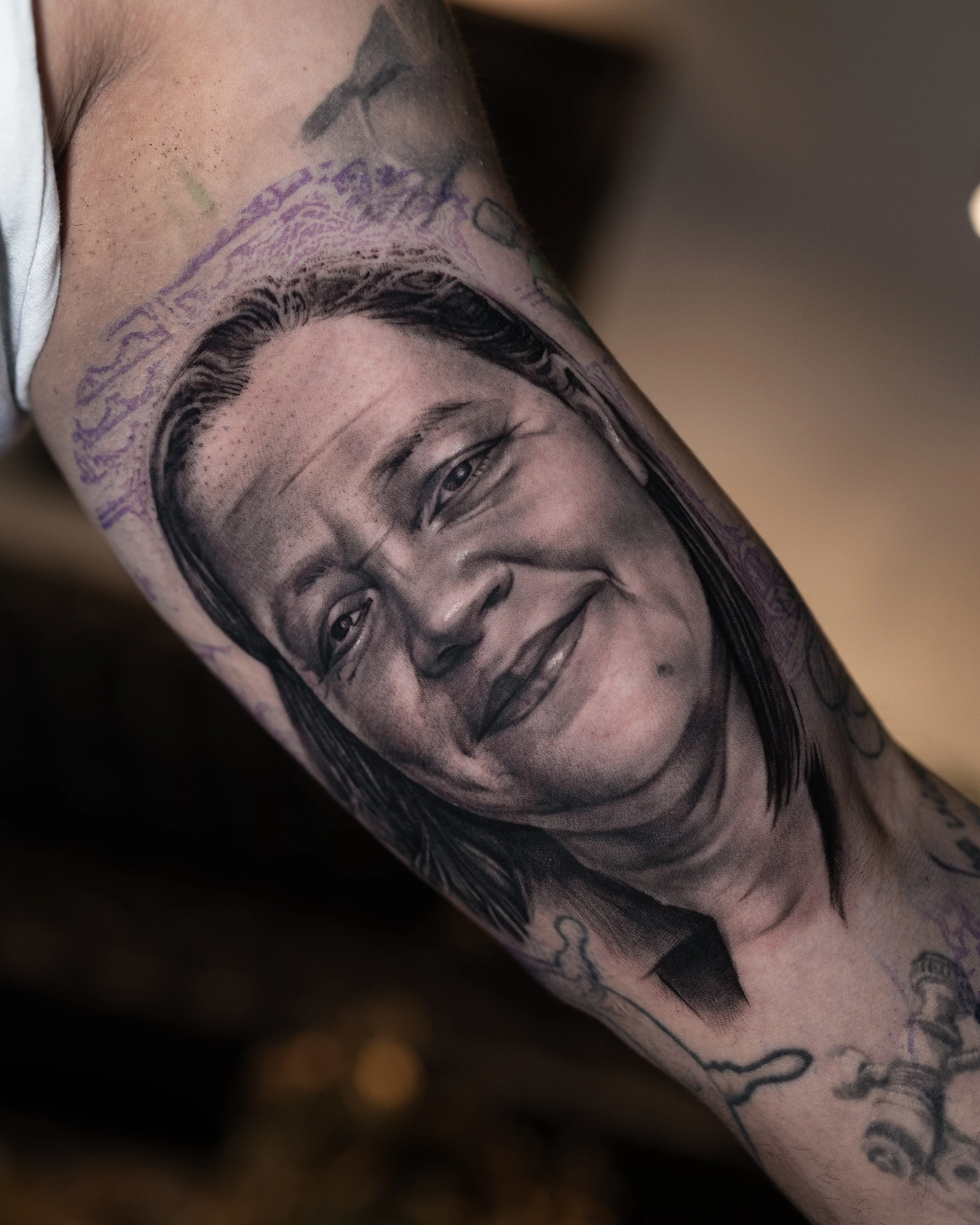 Black-and-grey realism portrait of a smiling person with long hair, fresh ink — Hector Rodriguez Goderich