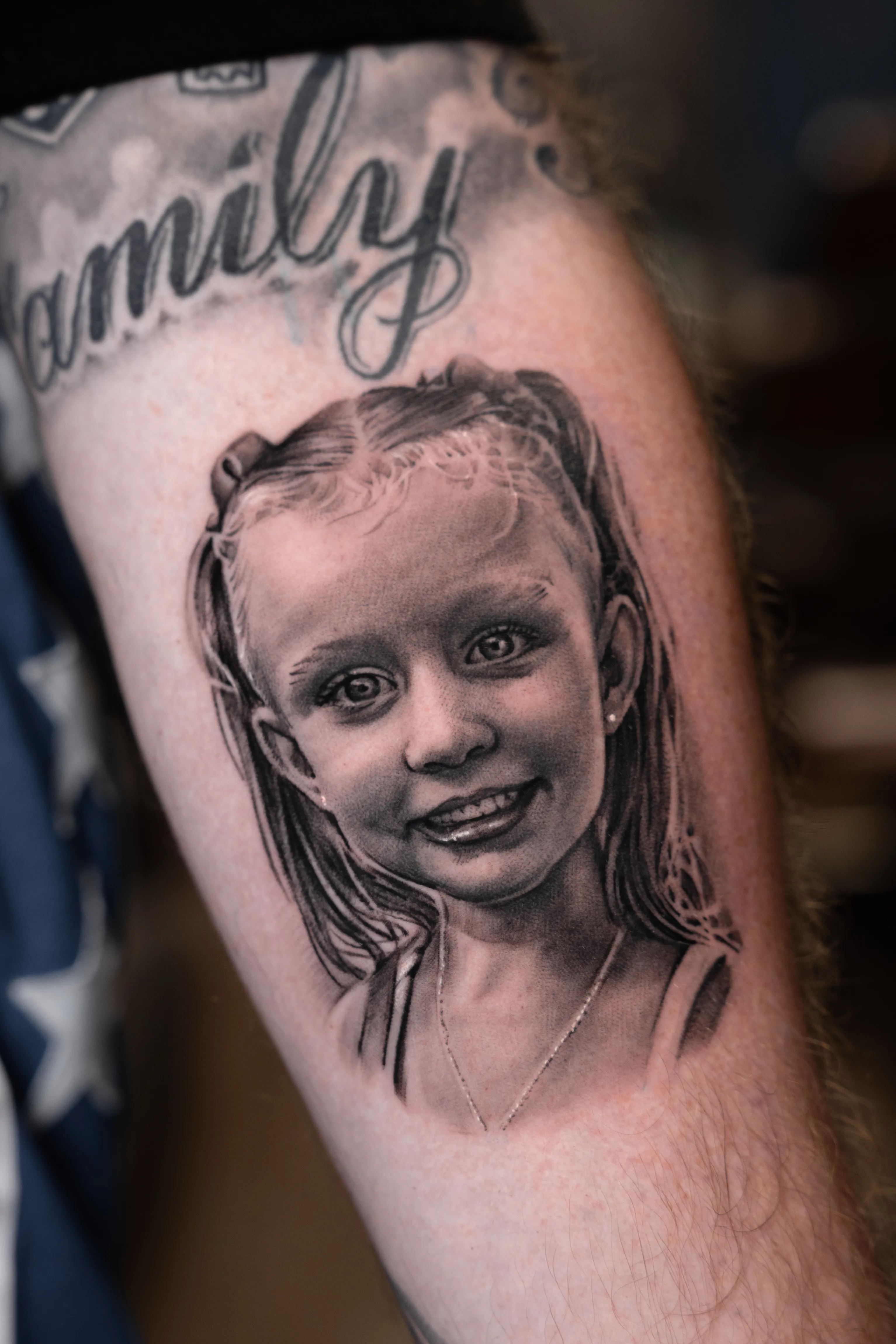 Black-and-grey realism portrait of a young girl beneath a 'Family' script — TKOTATTOO Fort Lauderdale